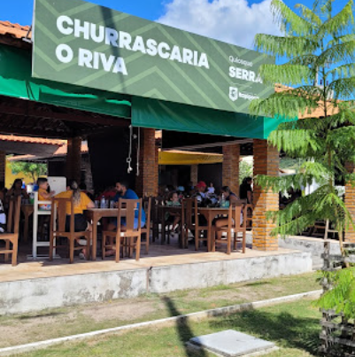Fachada verde da Churrascaria O Riva com mesas ao ar livre